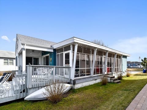 Relax in the screened-in porch, ideal for unwinding after a day at the beach, while enjoying views of the lush green lawn and nearby surroundings.