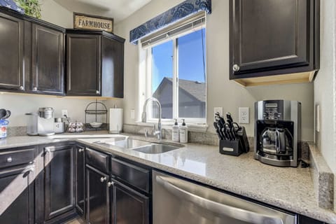 The kitchen features light-colored countertops and dark cabinetry, providing a practical workspace. Enjoy a complimentary coffee station with pods and a fully stocked kitchen equipped with professional-grade appliances for your stay.