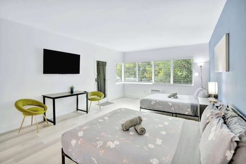 Open layout with 2 queen beds, Smart TV, and workspace under the TV with 2 chairs.