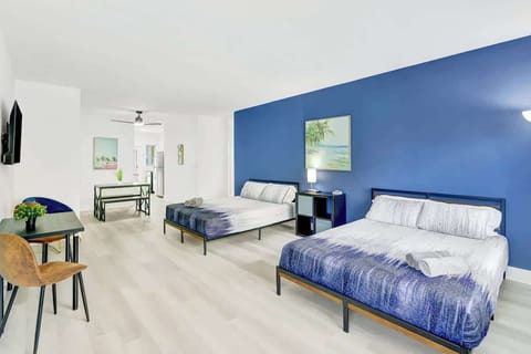 Open-concept living area with two queen beds, Smart TV, workspace, and A/C.