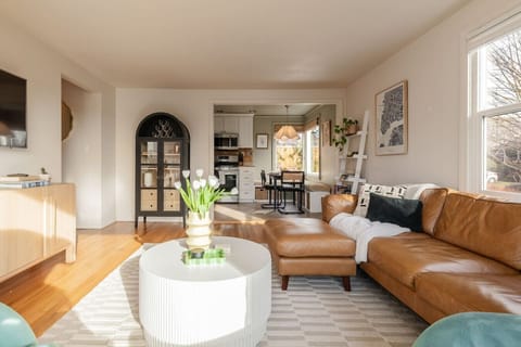 Living Room into Dining (wide) An open, connected floor plan that flows effortlessly from the living area through to the dining nook and kitchen. The arched display cabinet adds an architectural note that grounds the space.