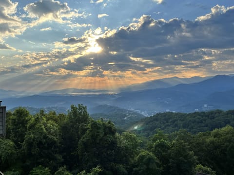 Golden-hour mountain panorama with sunbeams over lush valleys