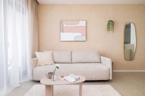 A comfortable beige sofa sits in the living room, complemented by a minimalist coffee table and subtle greenery.