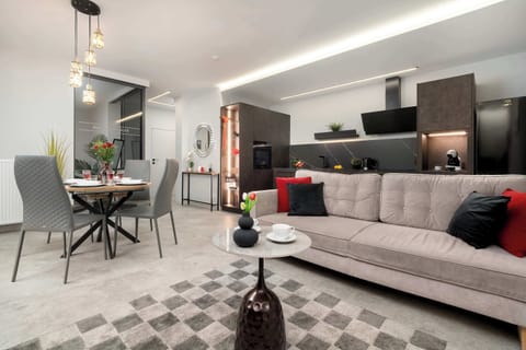 A spacious living room features a comfortable grey sofa with red accents and a modern dining area.