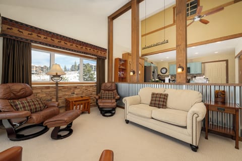 Unwind in your cozy mountain retreat at Mountainside Unit B-8 with rustic charm, leather seating, and stunning winter views through expansive windows.