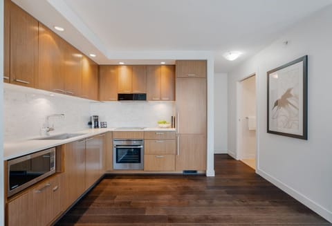 The sleek kitchen, adorned with warm wooden cabinetry and contemporary appliances, provides an inviting space for culinary creativity and social gatherings.