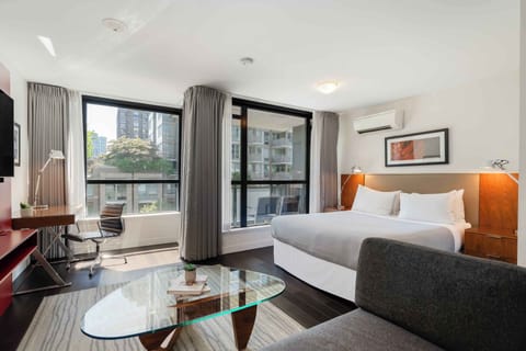 Bright living room with a comfortable sofa, glass coffee table, and large windows bringing in natural light from downtown Vancouver.