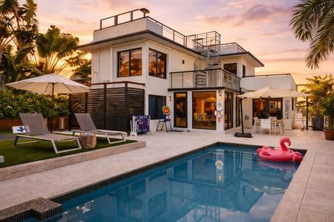 Resort-style backyard at sunset—private pool & spa, lounge chairs + umbrella seating, and a rooftop deck for golden-hour views.