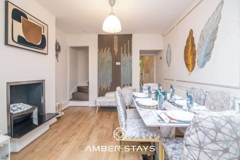 An elegant dining space featuring a marble table and patterned chairs, accented by contemporary leaf wall art and a sleek fireplace.