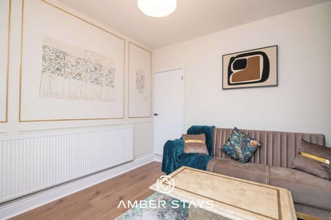 Minimalist abstract art and a velvet tufted sofa with teal accents create a sophisticated, modern vibe in this cozy room. A marble coffee table and patterned rug complete the sleek look.