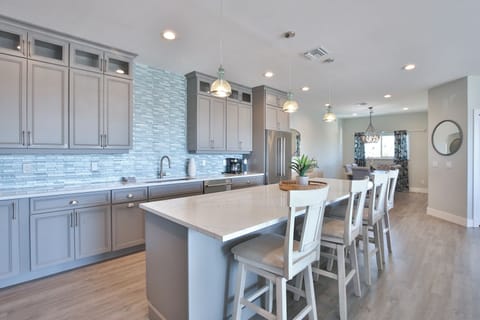 Your gourmet kitchen awaits with sleek gray cabinetry, stunning blue tile backsplash, and spacious island seating for memorable meals together.