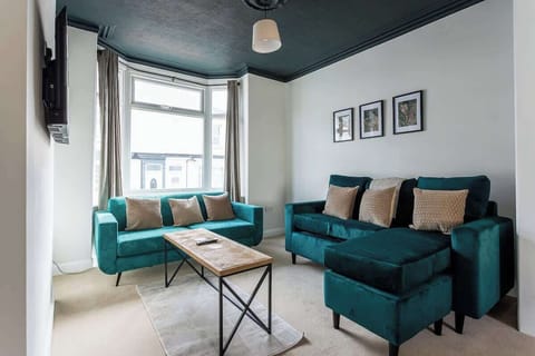Relax in the spacious living room, featuring comfortable sofas and a large TV, perfect for unwinding.
