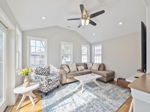 A charming living area with comfortable seating and large windows offers a perfect spot for gathering and enjoying the sunshine.