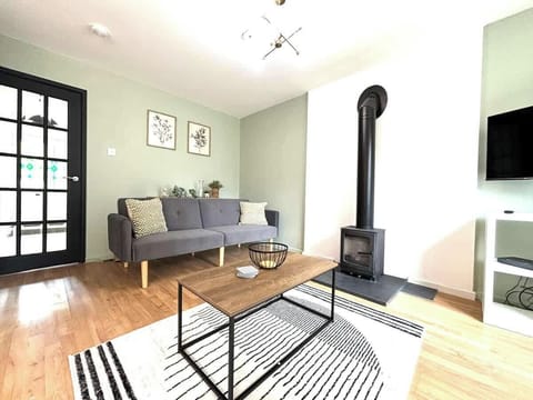 Bright and cozy living room with a wood-burning stove, smart TV, and comfortable seating.