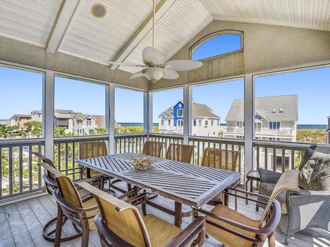Enjoy tranquil moments in this screened-in porch with elegant wooden furnishings and serene views of the ocean beyond.