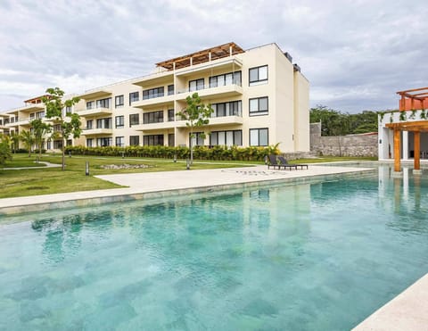 Shared resort-style pool framed by modern buildings & tropical landscaping