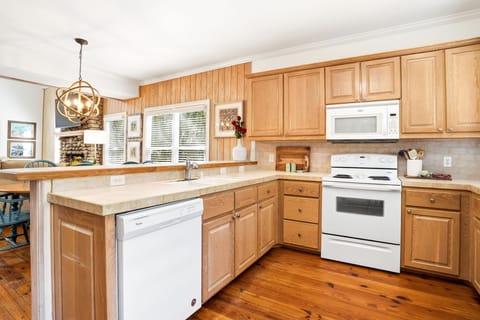 Open Kitchen with Breakfast Bar Seating - Natural wood cabinetry, wraparound counters, and bar seating that looks straight into the living room. Open enough to cook, pour a drink, and stay in the conversation.