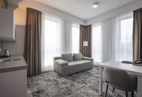 Relax by floor-to-ceiling curtains in a calm, airy lounge.