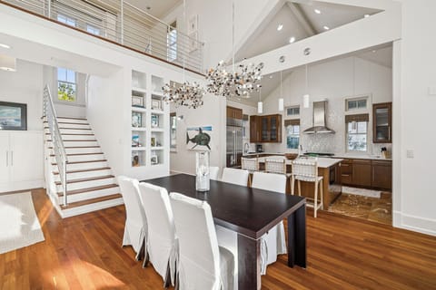 Step into this stunning open-concept space where soaring ceilings and elegant chandeliers create your perfect gathering spot for memorable meals.