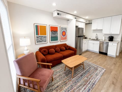 Colorful retro-inspired living room with comfortable seating beside the fully equipped kitchen.