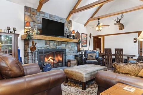 Vaulted ceilings, exposed wood beams, and a grand stone fireplace create the perfect cozy mountain retreat—ideal for gathering, unwinding, and warming up after a day at the lake.