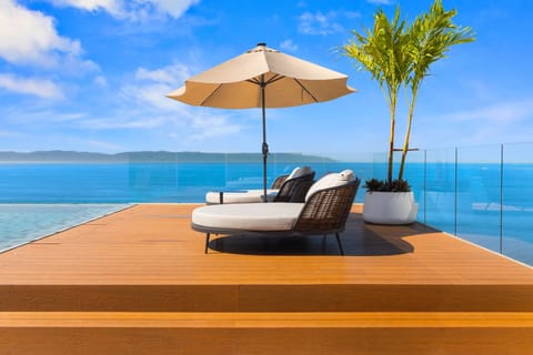 Relax on the luxurious rooftop deck featuring a private daybed, panoramic ocean views, and the perfect setting for sunset lounging.