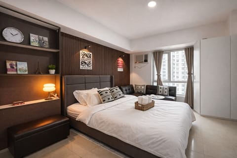 Spacious, bright studio with a comfy bed, cozy seating area, and large windows with city views.