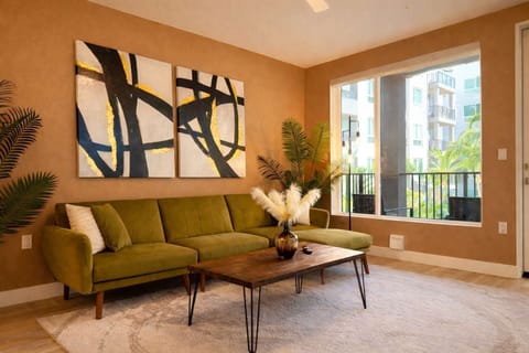 Spacious living room featuring a cozy L-shaped sofa, a full-size air mattress, and a 65" Smart TV with preloaded access to Netflix, Hulu, and Disney+, all set up for your enjoyment.