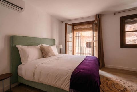 Dormitorio con cama doble, cabecero tapizado y balcón