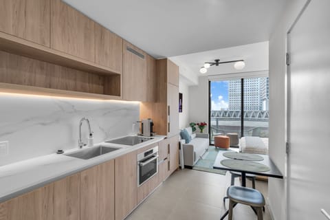Cook in style in our sleek, modern kitchen featuring light wood cabinetry, a beautiful marble backsplash, and high-end appliances (refrigerator, freezer, stove, microwave, dishwasher, stove)
