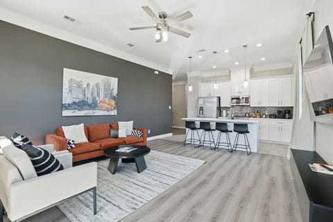 Modern open-concept living area with cozy seating and a fully equipped kitchen. Features include stainless steel appliances, island bar seating, high ceilings, and stylish décor—perfect for relaxing or entertaining.