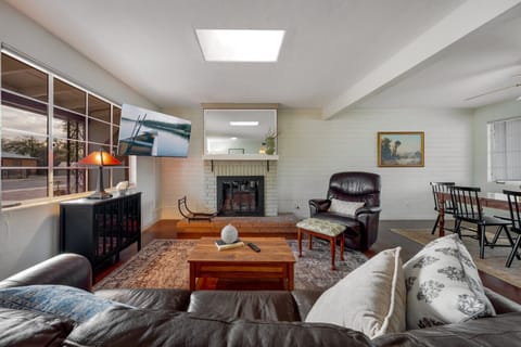 Settle into the living room with brick electric fireplace, smart TV, skylight, and cozy seating — ideal for movie nights or a quiet evening in