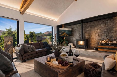 Unwind by the stone fireplace in our dramatic living room, where floor-to-ceiling windows frame breathtaking mountain views - the perfect end to a day of adventure