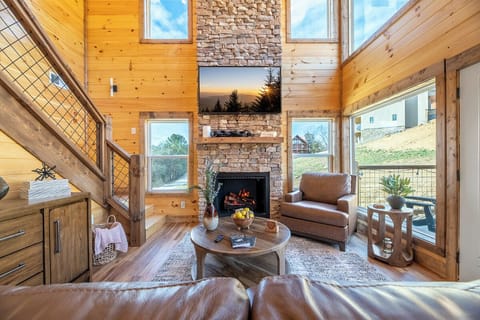 Unwind in your cozy living room by the stone fireplace, surrounded by warm wood and natural light streaming through expansive windows.
