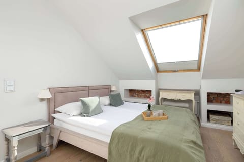 A cozy bedroom featuring a comfortable double bed with a green throw, illuminated by a large skylight that fills the space with natural light.