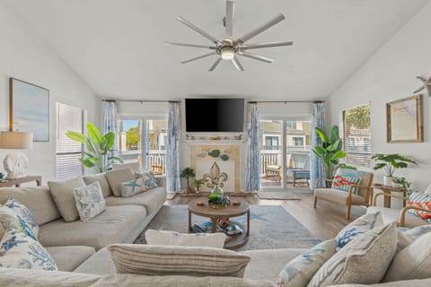 Relax in your spacious living room with vaulted ceilings, cozy sectional seating, and tropical plants that create a bright, airy atmosphere.