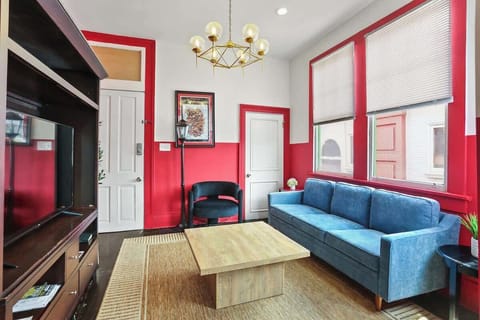 Bright living area with comfortable seating, Smart TV, and large windows that bring in natural light. Stylishly designed with bold accents and a relaxed layout, perfect for unwinding after a day exploring the city.