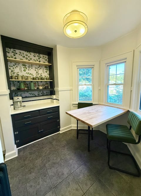 Breakfast nook and coffee station equipped with a coffee maker, electric kettle, french press, and large mugs.