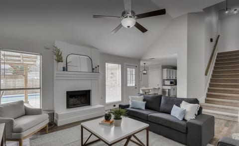 A bright, cozy living room with soft neutrals, a fireplace, and a comfy gray sofa. It feels warm, open, and perfect for relaxing.