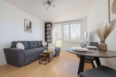 Bright living room with a comfortable sofa, dining table and large windows providing plenty of natural daylight.