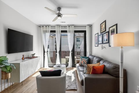 Sunlit living room with balcony access + smart TV.