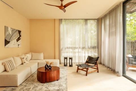 Lounge on the plush sectional beside sunlit floor-to-ceiling drapes.