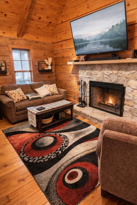 Cabin inspired living area with fireplace large TV and warm wood finishes creating a true home away from home