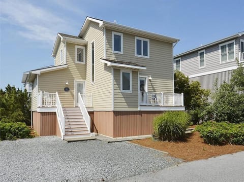 This charming coastal home showcases a welcoming exterior with a bright façade and inviting steps leading to a spacious porch.