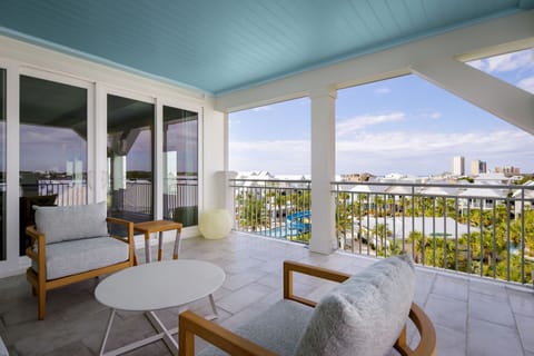 A balcony seating area invites you to unwind, featuring contemporary furniture beneath a charming blue ceiling, ideal for enjoying coastal views.