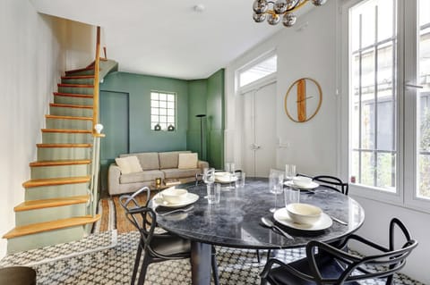 Canapé convertible en lit et coin repas, dans un espace moderne et lumineux avec escalier.