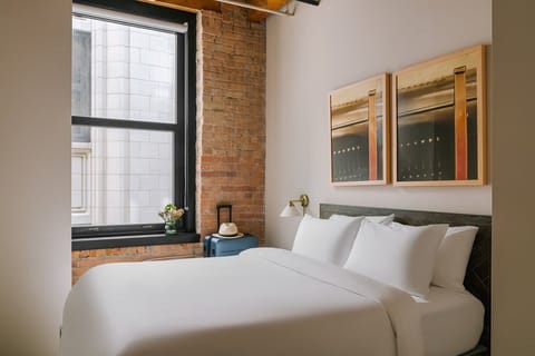 Spacious one bedroom with exposed brick, large windows, separate living room, 50 inch smart TV, and queen bed with hotel quality linens