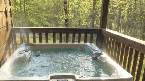 Private hot tub on the covered deck surrounded by lush trees at A Windy Ridge cabin in Wears Valley, Tennessee near Pigeon Forge and Gatlinburg.