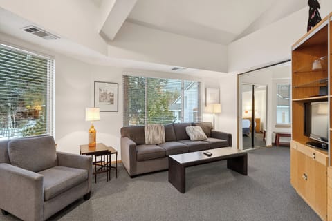 Bright, vaulted living space with large windows, sleeper sofa, and an open flow to the bedroom — perfect for relaxing after a day in Lake Tahoe.