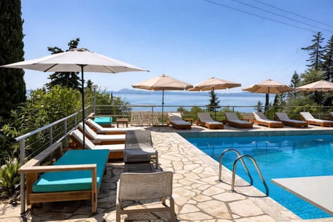 Elegant pool terrace with sun loungers and umbrellas facing uninterrupted sea views. A tranquil space to unwind, soak up the sun, and enjoy the peaceful surroundings.